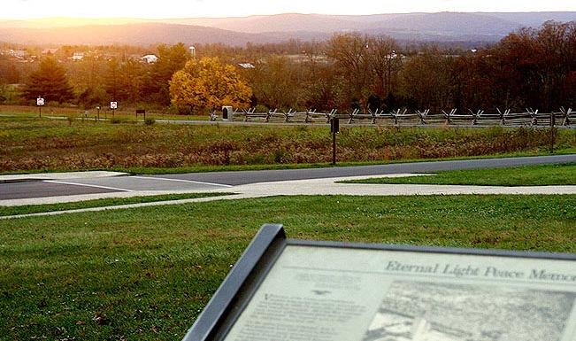 The Eternal Light Peace Memorial at dusk, fields and a fence with distant monuments