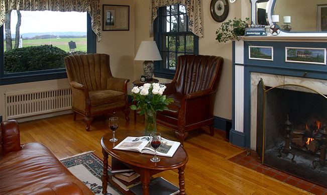 The parlor with a fireplace, leather chairs and a view over the battlefield fields